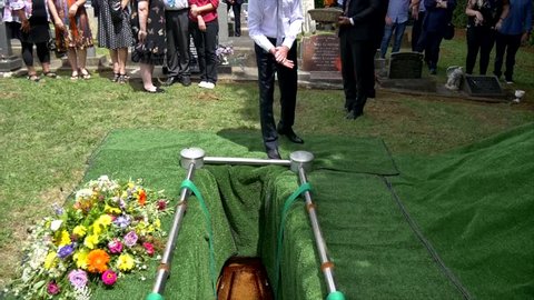 casket being lower into burial site at cemetery
