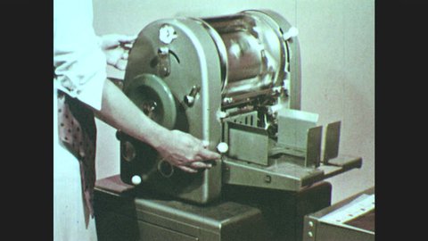 1950s: Woman runs copies on mimeograph.