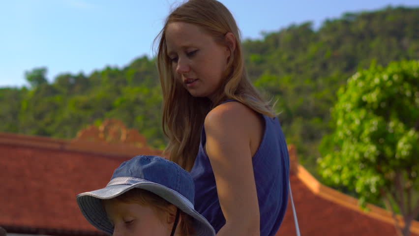 Tourists mother and son looking at a lotus plants in a huge ceramic vessel with water inside of a buddhist temple on Phu quoc island, Vietnam
