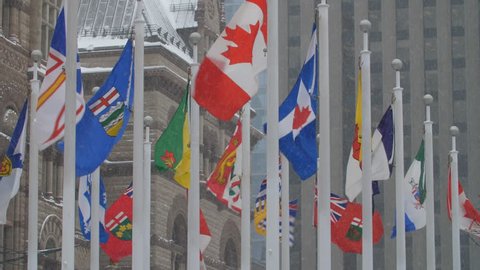 Flags of Canada and Canadian provinces. Snow falling. Old City Hall, Toronto.