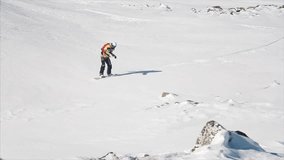 Happy snowboarder having fun snowboarding backcountry on a sunny winter day in snowy mountains. Video. Extreme freeride snowboarder riding fresh powder snow off piste in mountain ski resort
