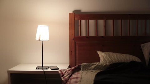 Man goes to sleep. Person lies down in bed and turns off night stand lamp