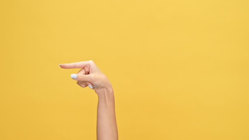 Woman hand pointing at someone over yellow background Royalty-Free Stock Footage #1007574775