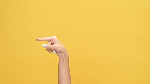 Woman hand pointing at someone over yellow background