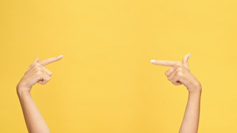 Woman hands pointing on copyspace and showing thumbs up over yellow background

