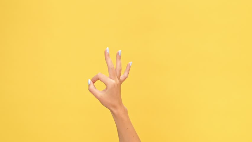 Woman hand showing ok gesture over yellow background Royalty-Free Stock Footage #1007574922