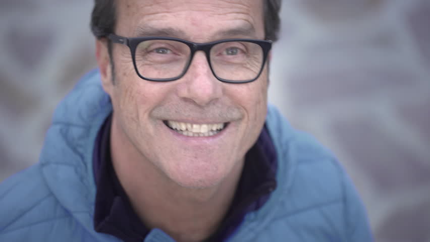 Portrait of attractive mature casual confident happy man dressed with a light blue jacket looking at camera and smiling in a spring day. 