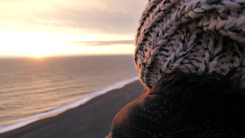 GIRL LOOKING AT A SUNSET IN ICELAND BEACH