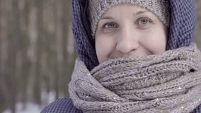Girl in white mittens drinking from a dark mug. Big shot. Scarf and hat under the hood. Blue jacket. Winter forest. Blurred background. The tourist and traveler. 4K video