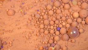 Beautiful Abstract beige background with bright bubbles of vivid paint. Make-up. Beauty backdrop design. Liquid makeup foundation moving close-up. Macro shooting 4K UHD video