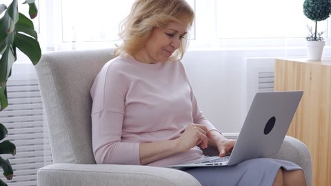 Pleased female with laptop in armchair