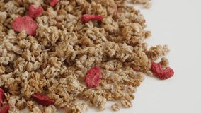 Pile of crunchy cereals tilting footage - Sweet and tasty muesli with dehydrated strawberries close-up 