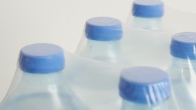 Close-up package of bottled water tilting footage - PET containers with transparent liquid slow tilt 