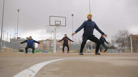 Street workout training. Low angle shot of sport group of young multi ethnic people practicing tai chi or qigong on the outdoor basketball court as part of a workout routine