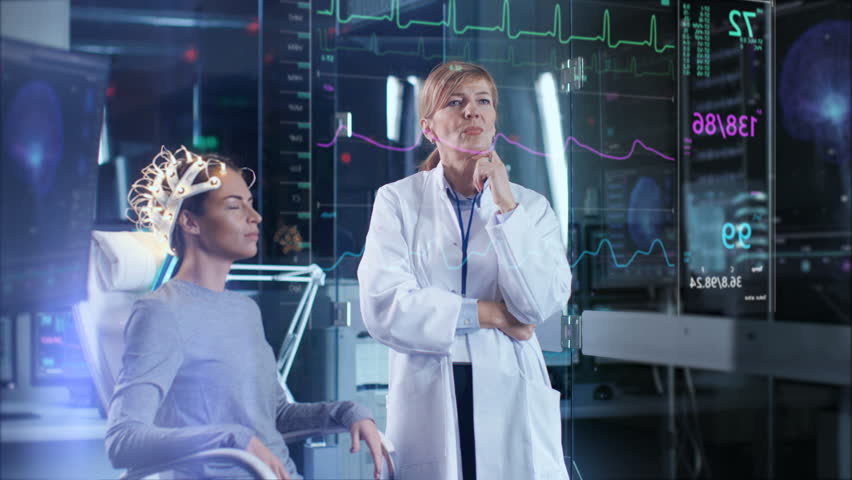 Woman Wearing Brainwave Scanning Headset Sits in a Chair while Scientist Swipes Augmented Reality Screen Showing Brain Model and EEG Data. In the Modern Brain Study Laboratory. Shot on RED EPIC-W 8K.