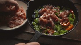 Man puts the chicken pieces into a frying pan with pepper. Video