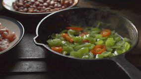 Pieces of chicken, beans. Green pepper and chili in a frying pan. Video