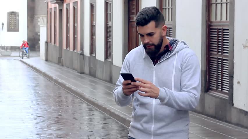 Euphoric man celebrating sport victory looking at smart phone in the middle of street road. Lucky young hipster acting exultant holding mobile in the city. On line bet win concept Royalty-Free Stock Footage #1007615014