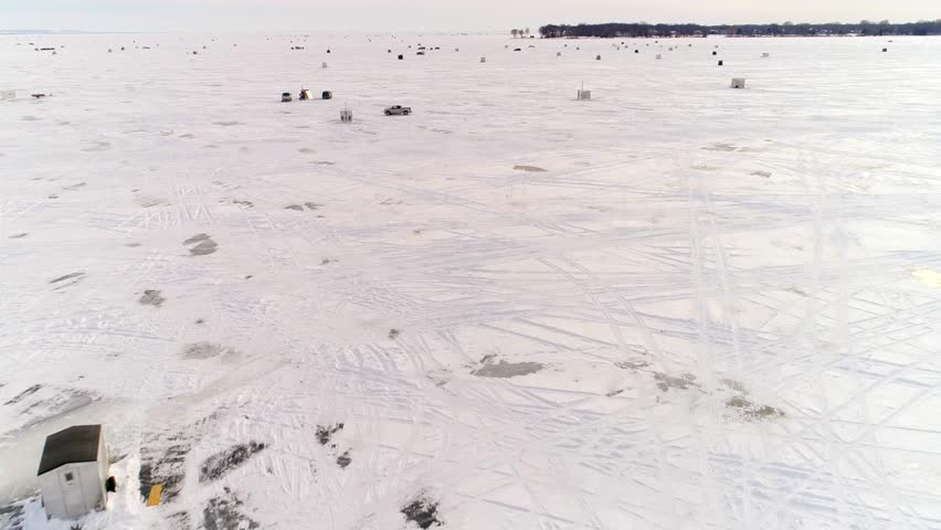 A community of ice huts in ice fishing and Sturgeon spearing season on Lake Winnebago, Wisconsin, time lapse aerial flyover.