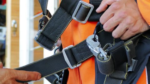Parachute jumping,skydiving activity. Instructor controlling and fixing harness before the flight for person's safety. Effective parachute equipment. Extreme sport 