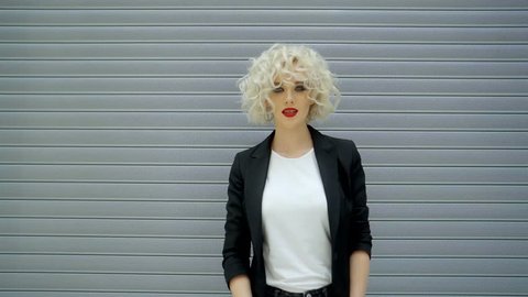 a young and beautiful lady with bright lipstick and curls on blond hair has a bright lipstick on her lips and dark shadows, a woman dresses stylish glasses