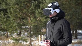 a person in virtual reality glasses controls a drone on the background of the forest