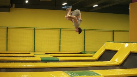 Unbelievable back double somersaults one after one performed by professional young male athlete on the trampoline.