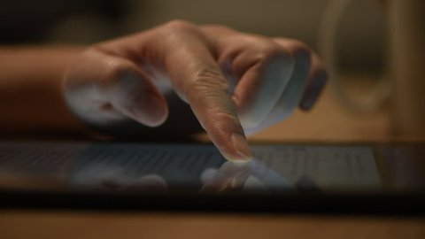 Woman reading online news on digital tablet, close up of hands using device