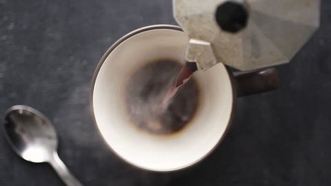 Super slow motion top view of coffee pour into cup from geyser coffee maker