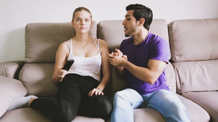 Young couple arguing because of TV remote control sitting on couch Royalty-Free Stock Footage #1007640427