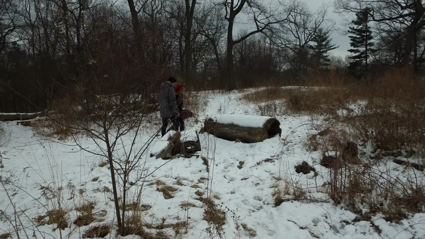 Couple sits on Snow Covered Log in Winter