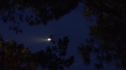 Helicopter flying in night operations with searchlight.