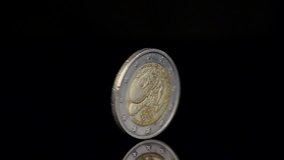 Two Euro coin spinning on black background. Close up slow motion shot.  - Powered by Shutterstock - Get 15% off with code: PIKWIZARD15