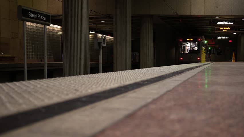 A Subway car departs at an underground train station at night - low angle