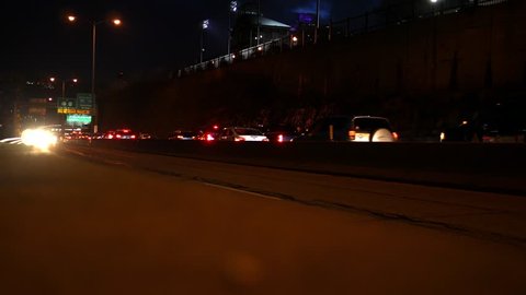 Outbound moving highway traffic at night as scene from near a guard rail