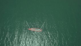 Top view of a red boat sailing in the blue sea.