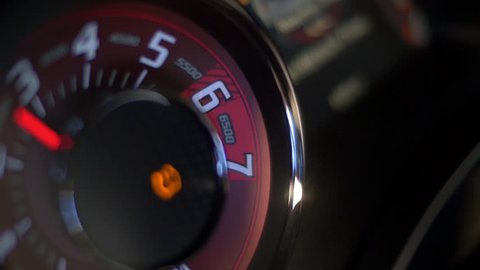 Tachometer on high-performance car, with needle jumping to redline.
