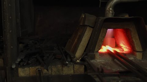 Working forging kiln with two billets inside. Flame is burning and warming, prepairing stage in processing of metal in a forge