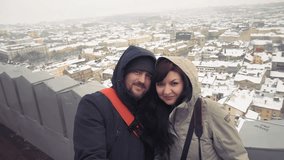 Young couple travelling in Ukraine taking selfies in Lviv by the panorama old city. Couple tourist in Lviv taking selfies with winter cityscape in the background. Couple taking selfie video in Lviv.