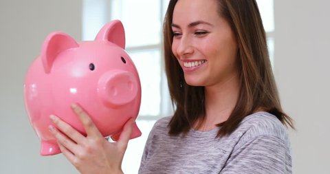 Beautiful young woman holding large pink piggy bank