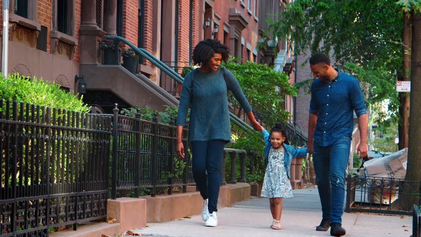 Young black couple swinging daughter as they walk in the street Royalty-Free Stock Footage #1007670562