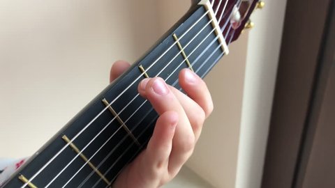 Close up of cute child kid fingers playing the guitar. Musica school for children. Musical chords.