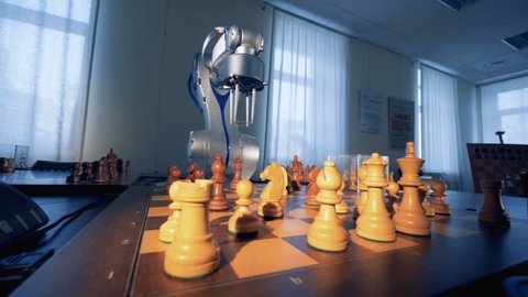 Artificial intelligence concept. Innovative modern robotic arm playing chess with a man. 4K.