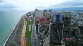 Aerial slow motion shot of Batumi's urban area, seafront road and sea with the view on the city from bird eye view perspective from above. Shot in 4k