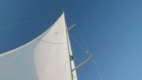 View of moon in day sky and white main sail