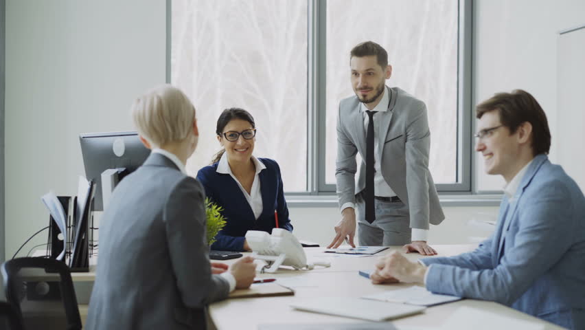 Businesswoman discussing reports with male and female colleagues sitting at the table in modern office | Shutterstock HD Video #1007692159