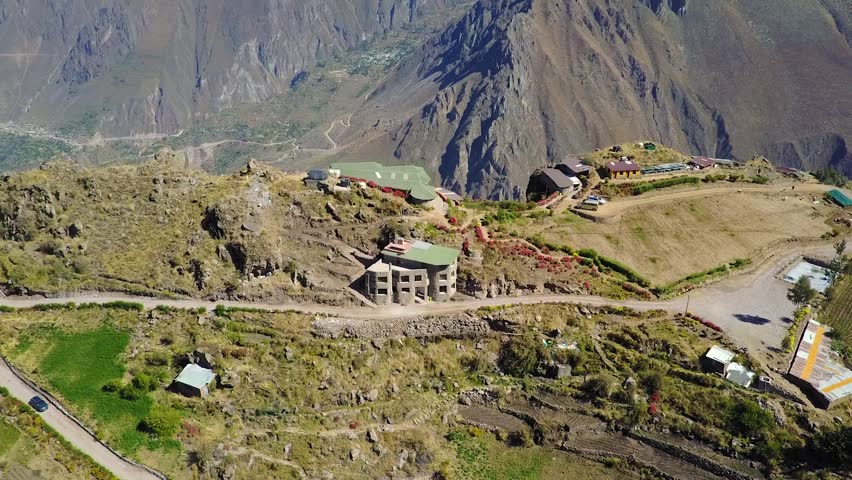 Amazing establishing shot flying over a beautiful house on the edge of a cliff overlooking the Colca Canyon in Peru