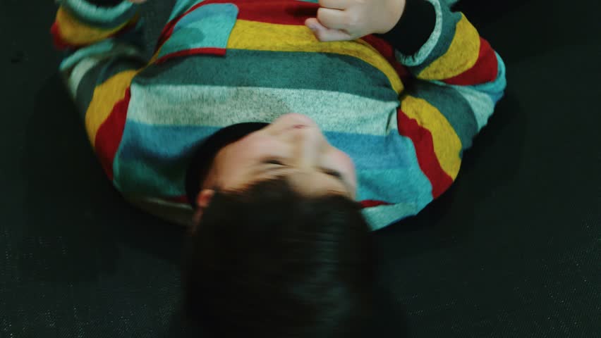 boy in a striped sweater twists and plays lying down