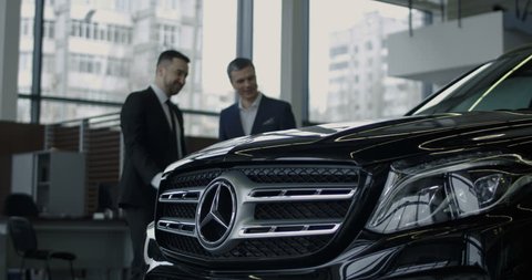 ZAPOROZHYE, UKRAINE, JANUARY 18, 2018: Elegant salesman presenting new Mercedes Benz car to potential buyer in showroom
