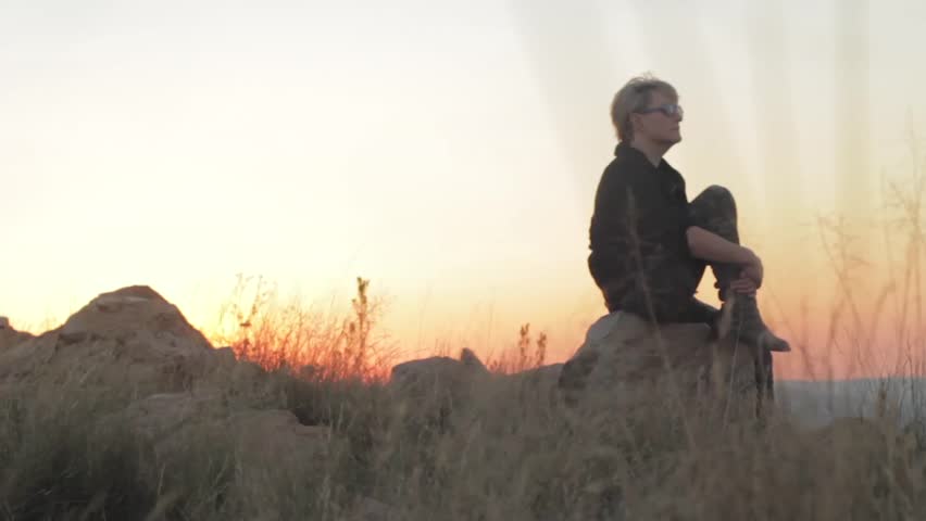 A woman admires a beautiful sunset on the top of an African Mountain